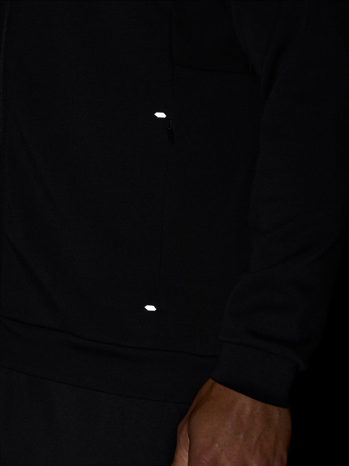 Detailed view of the zipper placket on the black Travel Zip Hoodie with a small Castore emblem.