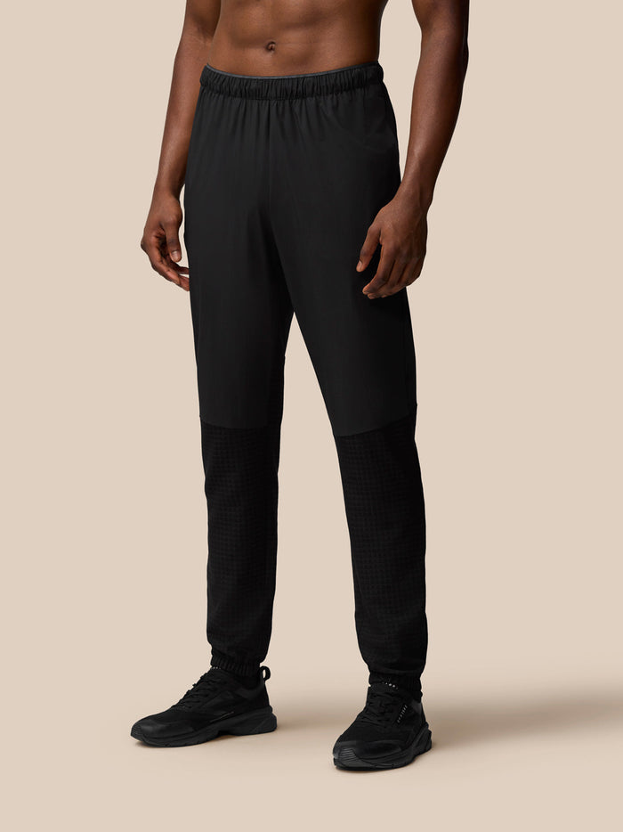 Front view of a man wearing black Flex Winterised Woven Joggers with elastic waistband and tapered cuffs