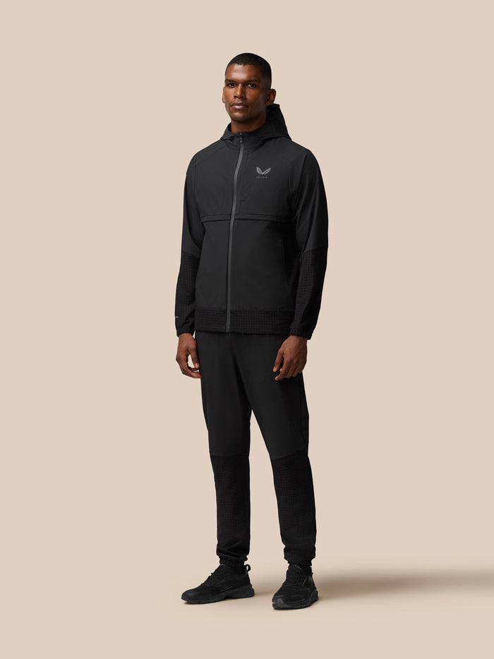 Full body shot of a man in black Flex Winterised Woven Joggers with a black athletic jacket