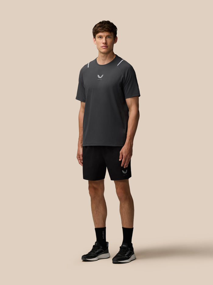 Male model wearing a dark athletic shirt with Castore logo against a beige background