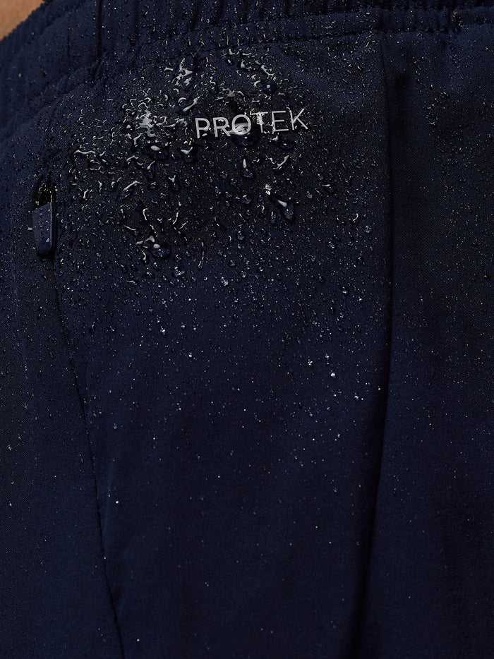 Close up of navy Apex shorts fabric with ProTek branding and water droplets beading on the surface.