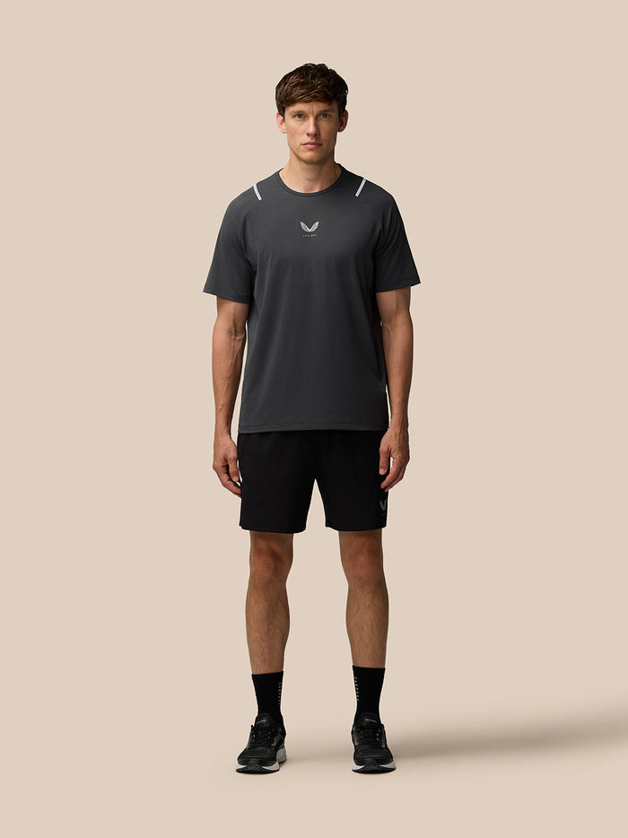 Male model wearing Apex Training T Shirt in gunmetal with reflective shoulder accents and black shorts.