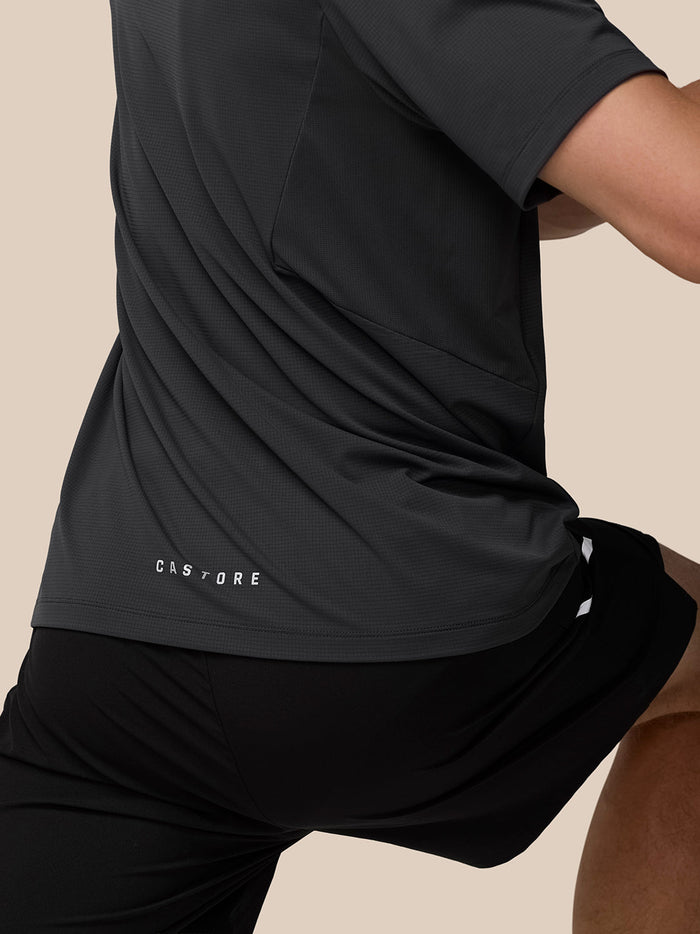 Full body shot of a man in the gunmetal Apex Training T Shirt with reflective shoulder details and black shorts.