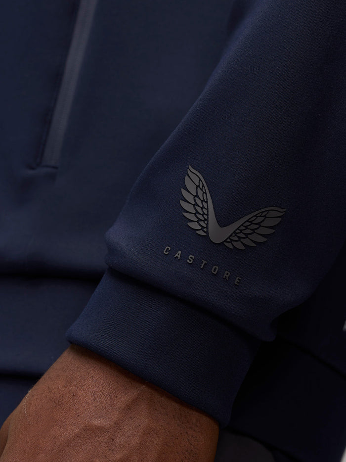 Close-up of navy hoodie sleeve showing the Castore wing logo near the cuff