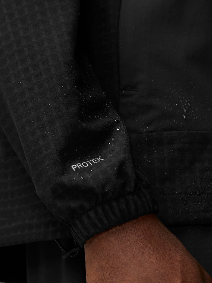 Close-up of black Flex Winterised Woven Jacket sleeve with ProTek branding and water droplets.