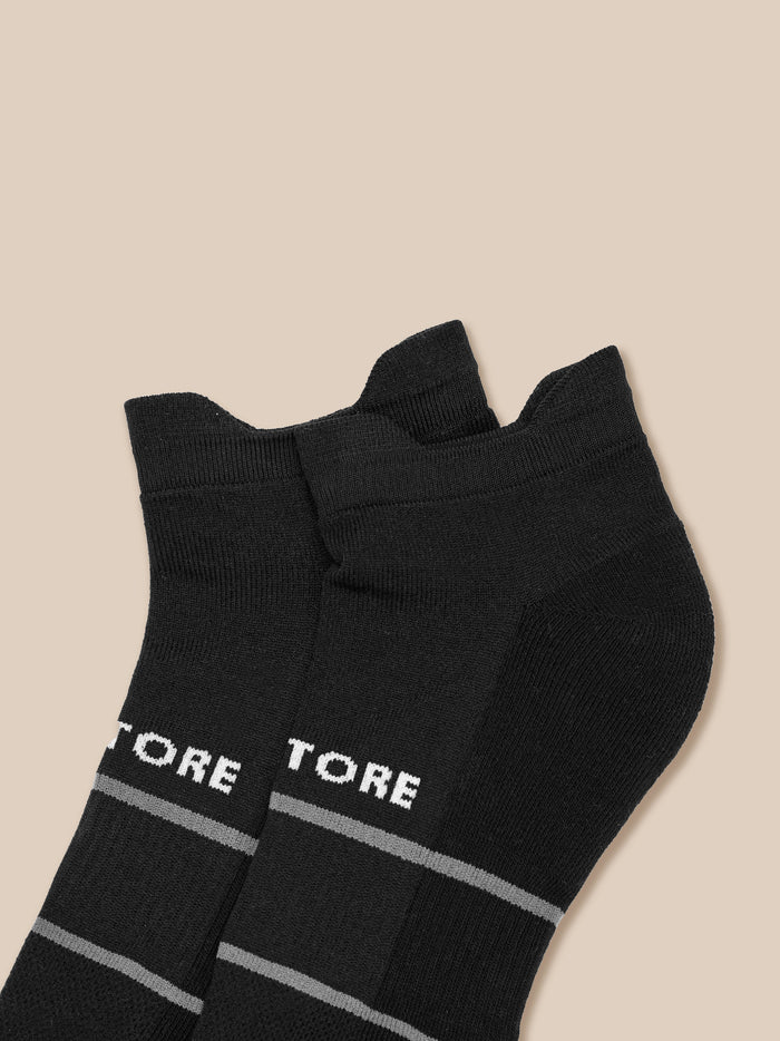 Close up of black athletic sock with Castore branding and gray banding shown from a different angle