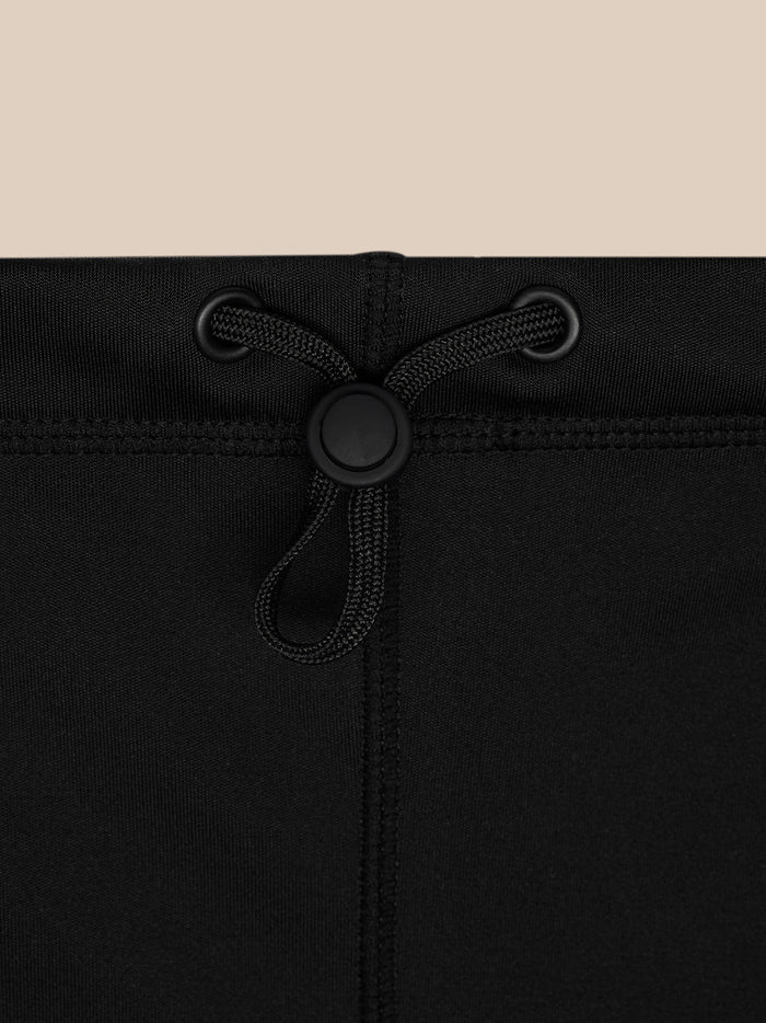 Close-up of the snood drawstring and round plastic toggle on black fabric