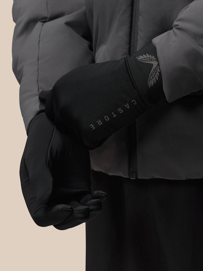 Close-up of black glove showing silver wing logo on the cuff and CASTORE branding along the forearm.