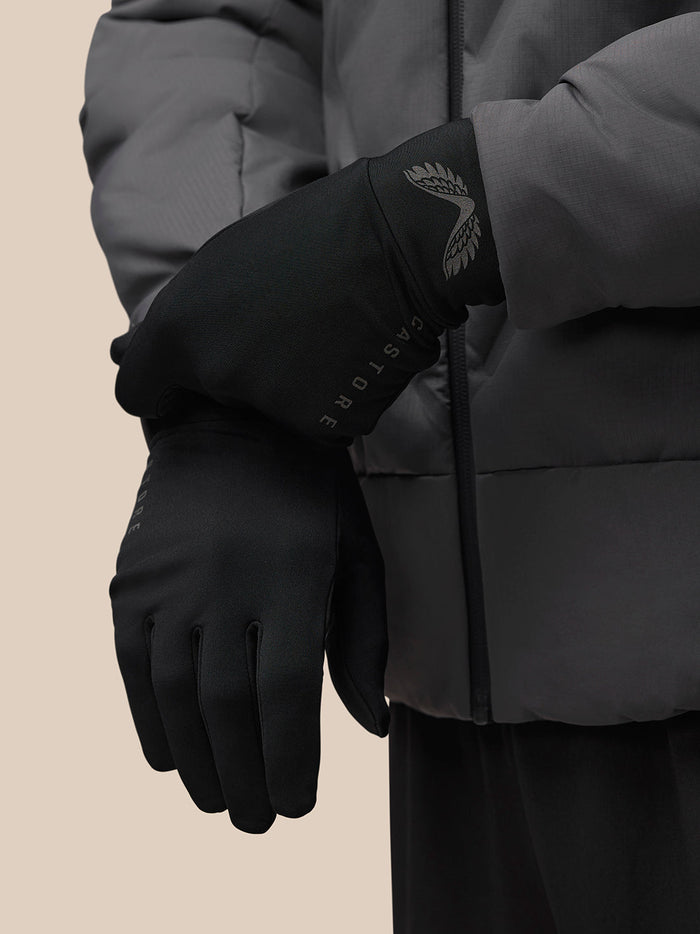 Gloved hand in a black winter glove with wing emblem and CASTORE lettering along the wrist area.