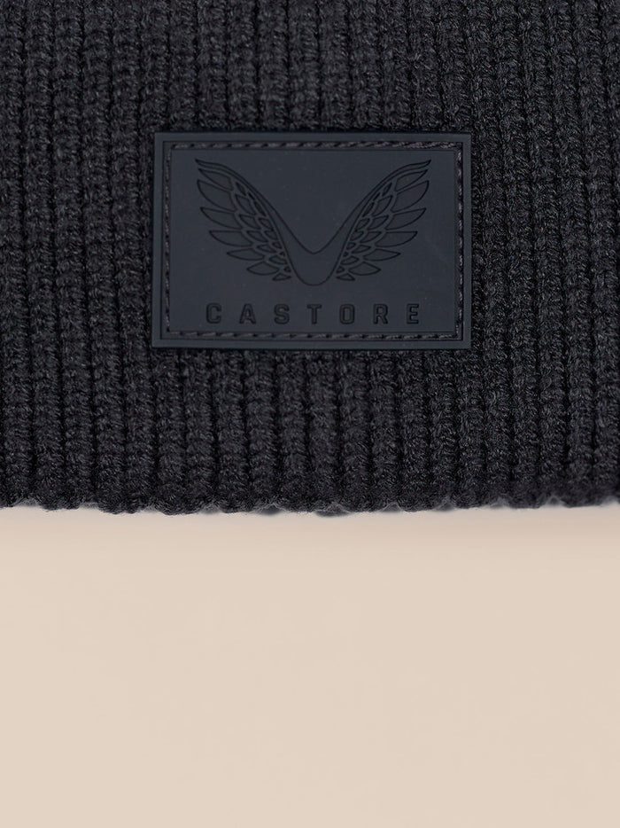 Castore logo patch on the cuff of a dark grey ribbed beanie.