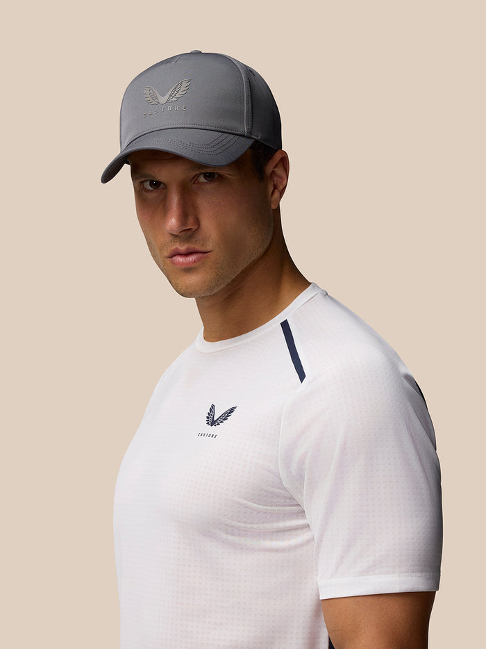 Profile shot of a male model wearing a charcoal nylon cap with Castore wing logo on the front.