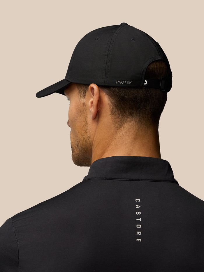Rear view of a black Castore cap with an adjustable back strap worn by a model