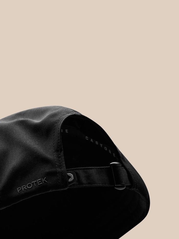 Close-up of black nylon cap showing an adjustable back strap and Castore branding