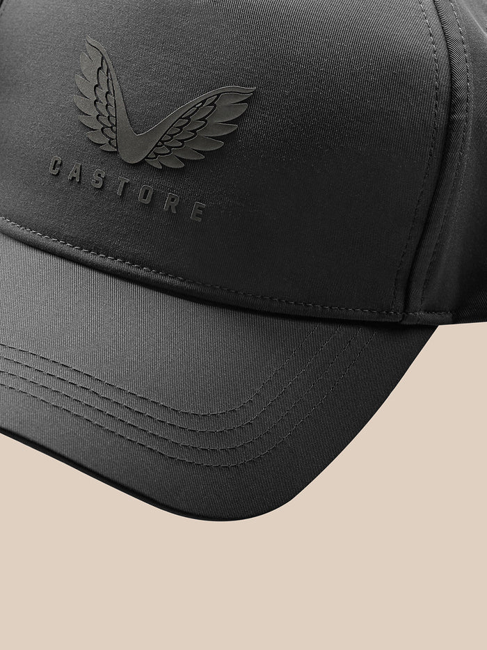 Man wearing charcoal Castore cap with wing logo on the front against a light background.