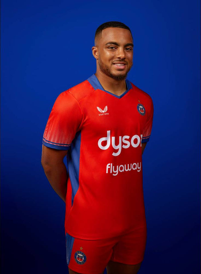 Model wearing red Bath Rugby Euro Cup Shirt with gradient sleeves and dyson sponsor against a blue backdrop