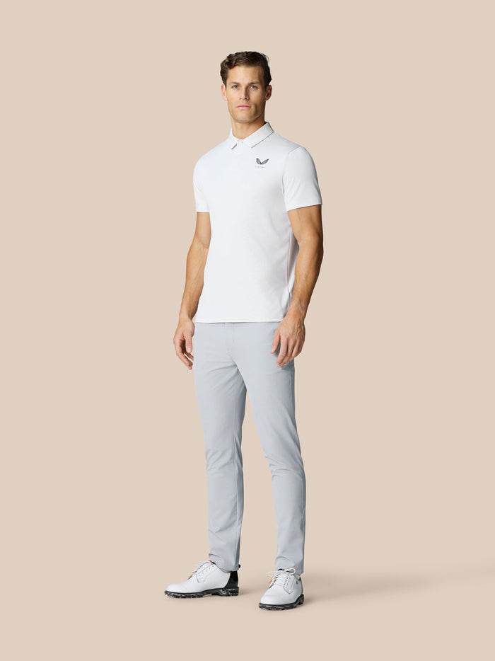 Male model wearing mid grey Golf Club Trousers with a white polo shirt.