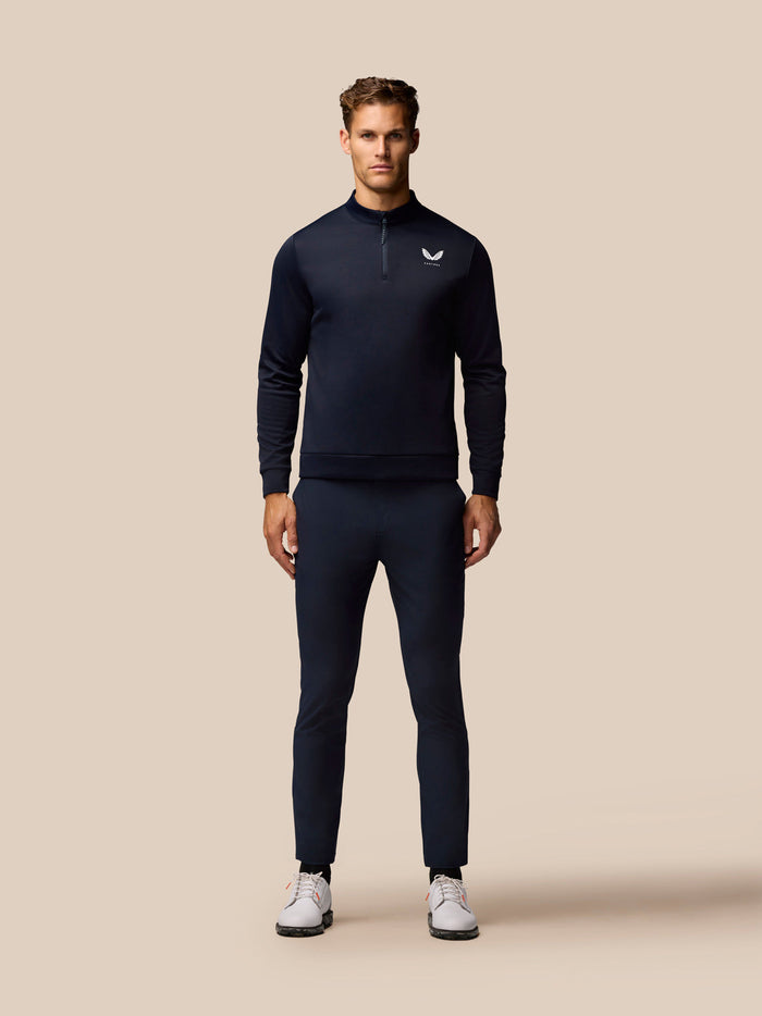 Full body shot of a male model in navy golf wear showing Golf Club Trousers 32 inch leg in Midnight Navy with a matching top and white sneakers