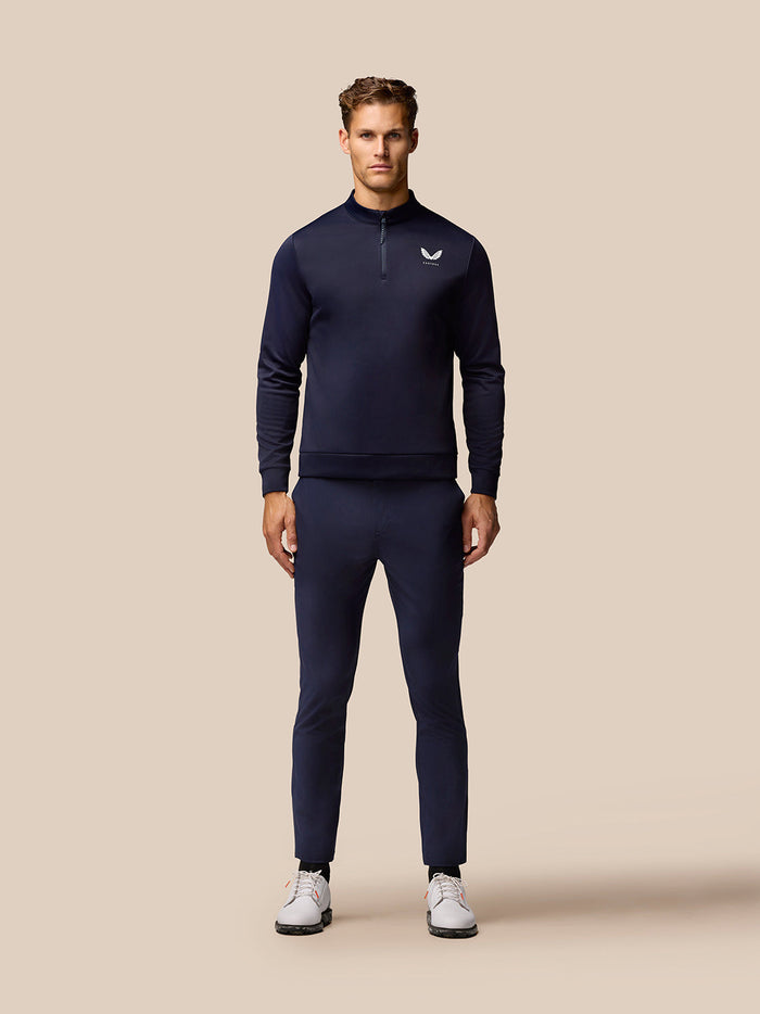 Full length shot of a man in navy Castore golf apparel with a zip neck top and matching trousers