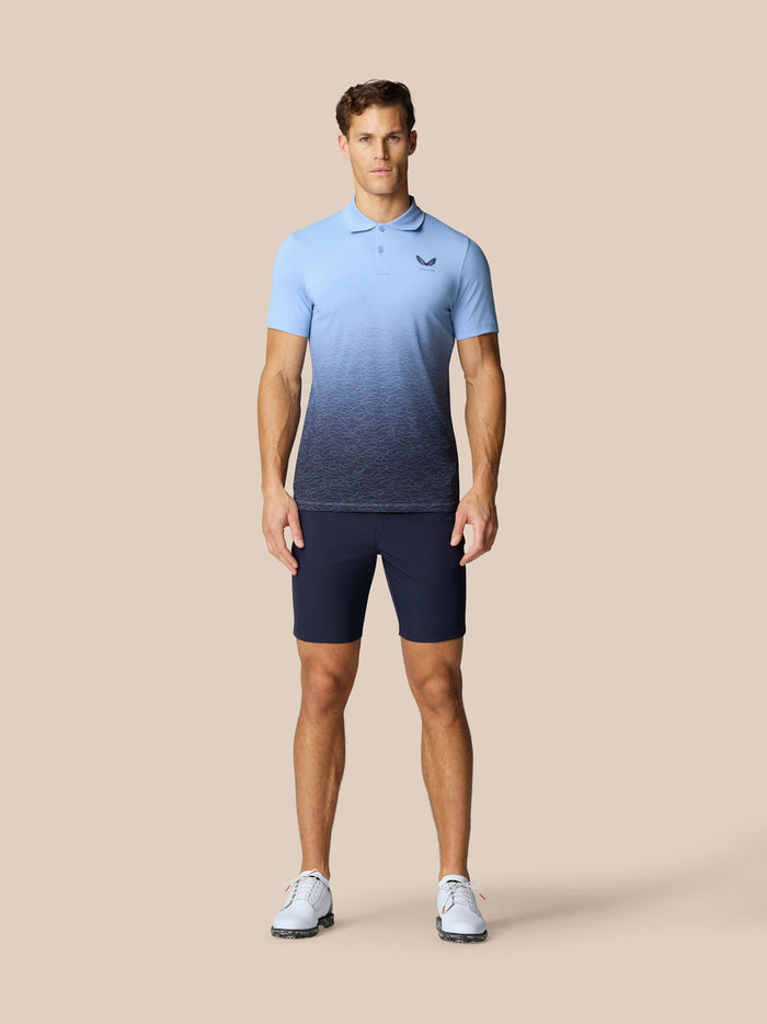 Male model wearing navy golf shorts with a light blue polo shirt and white sneakers.
