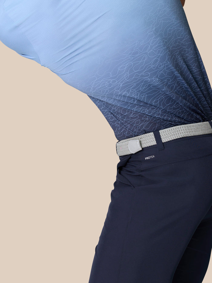 Close up of navy golf shorts with a light gray belt featuring ProTek branding at the back and droplets on the fabric.