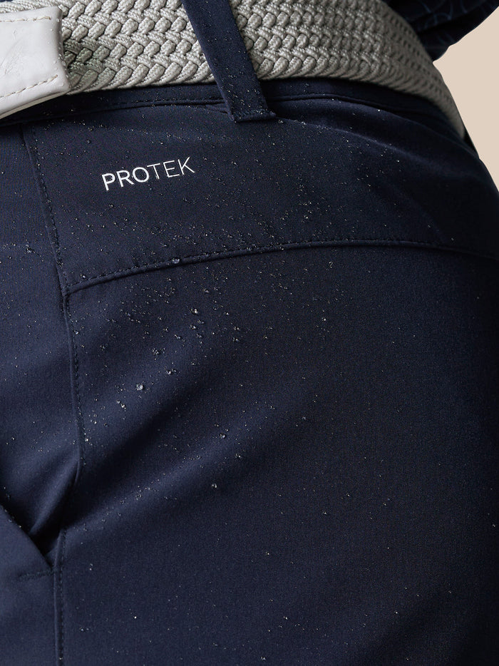 Close up of navy golf shorts waist area showing ProTek branding and a textured light gray belt.