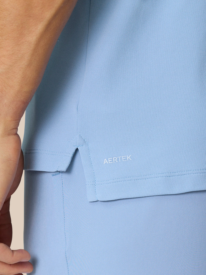 Close up of sky blue golf polo fabric showing AERTEK label and side hem slit.