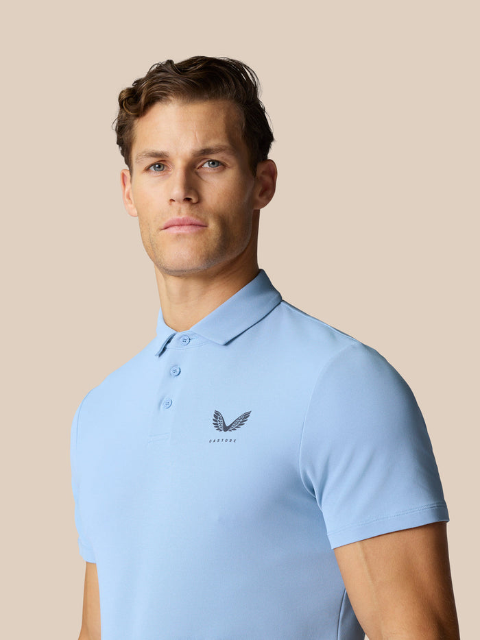 Male model wearing sky blue Golf Club Essential Polo with chest logo and polo collar.