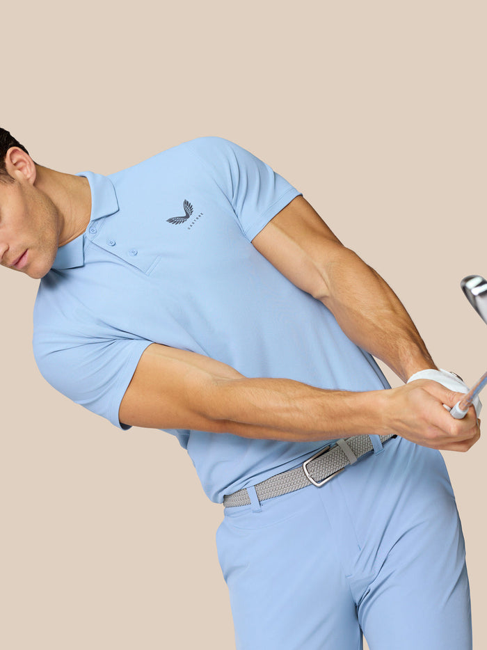 Rear and slight side view of a man in sky blue golf polo showing Castore logo on left chest and upper back