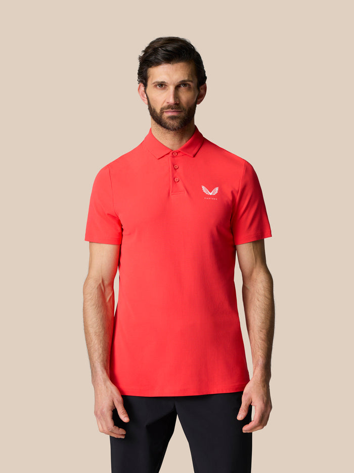 Male model wearing bright red Golf Club Essential Polo with a white Castore logo on the chest