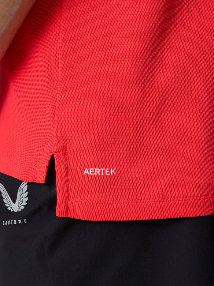 Close-up of the red Golf Club Essential Polo hem with AERTEK branding and a side slit.