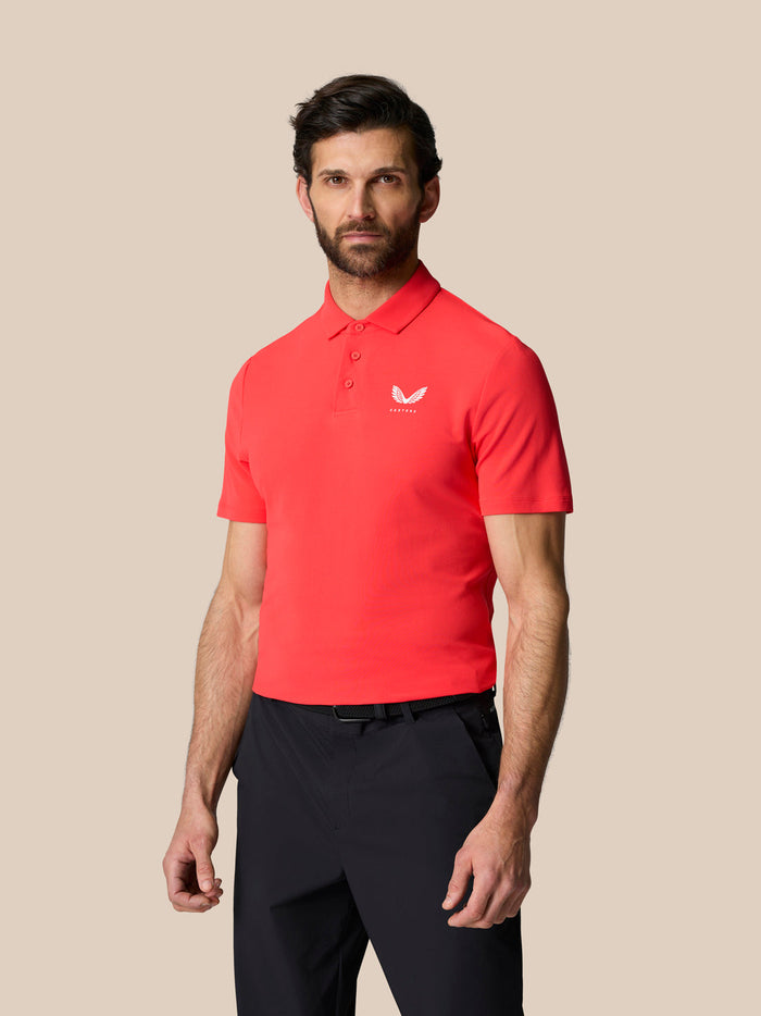 Male model wearing coral Golf Club Essential Polo with white Castore logo on left chest.