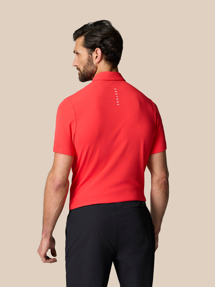 Back view of coral Golf Club Essential Polo showing vertical Castore branding along the upper back.