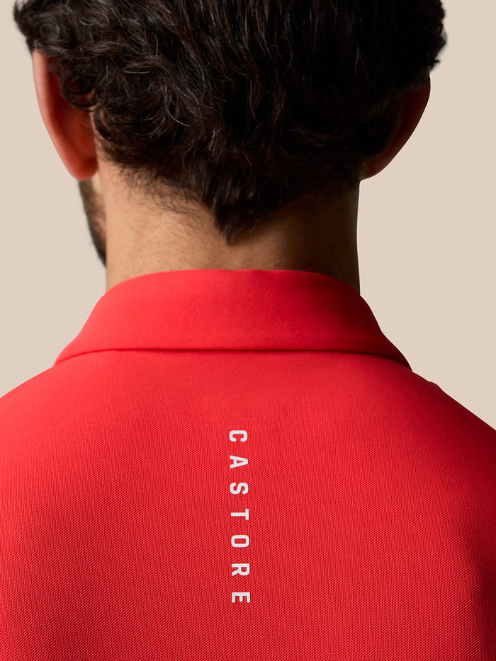 Back view of a man wearing the red Golf Club Essential Polo, showing Castore branding down the back.