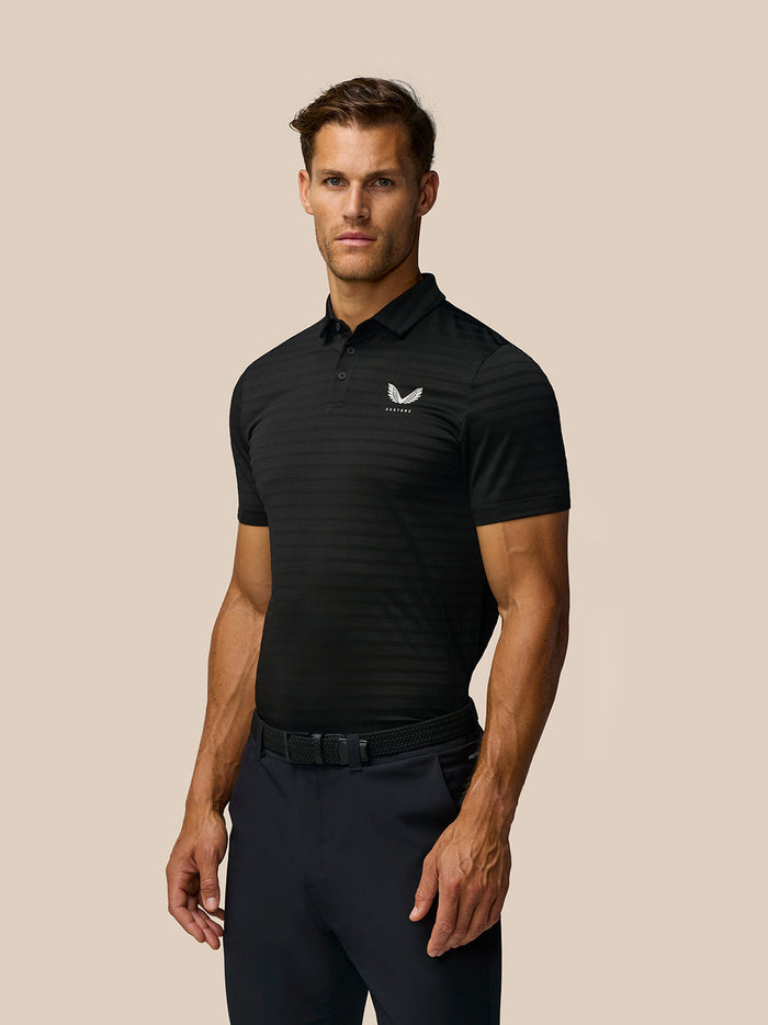 Male model wearing black Pinnacle Pique Stripe Polo with subtle stripes and Castore logo on chest