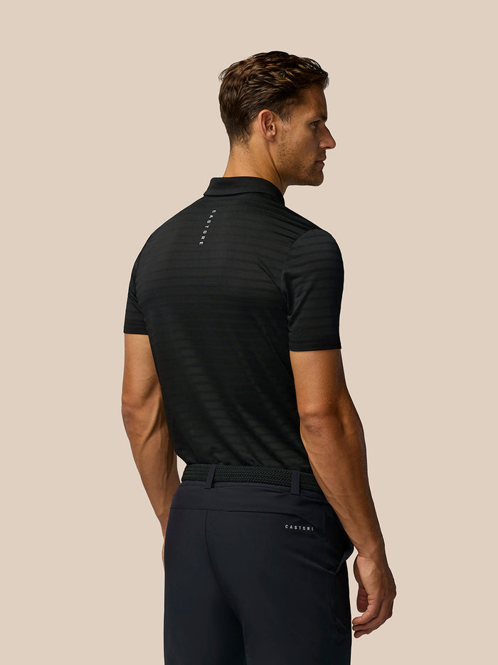 Back view of a man in the black Pinnacle Pique Stripe Polo with a striped knit and Castore branding on the upper back