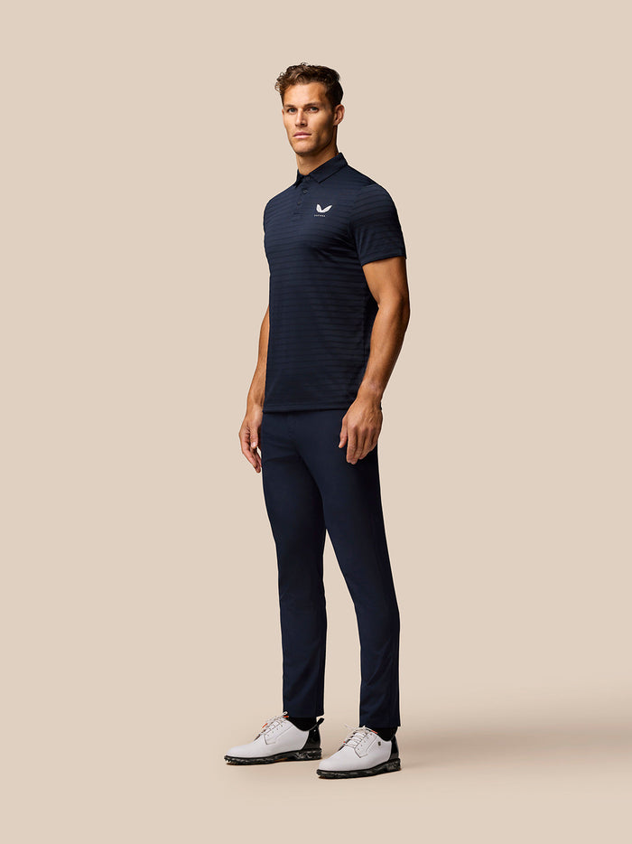 Male model wearing navy Golf Pinnacle Pique Stripe Polo with subtle stripes and Castore logo on left chest