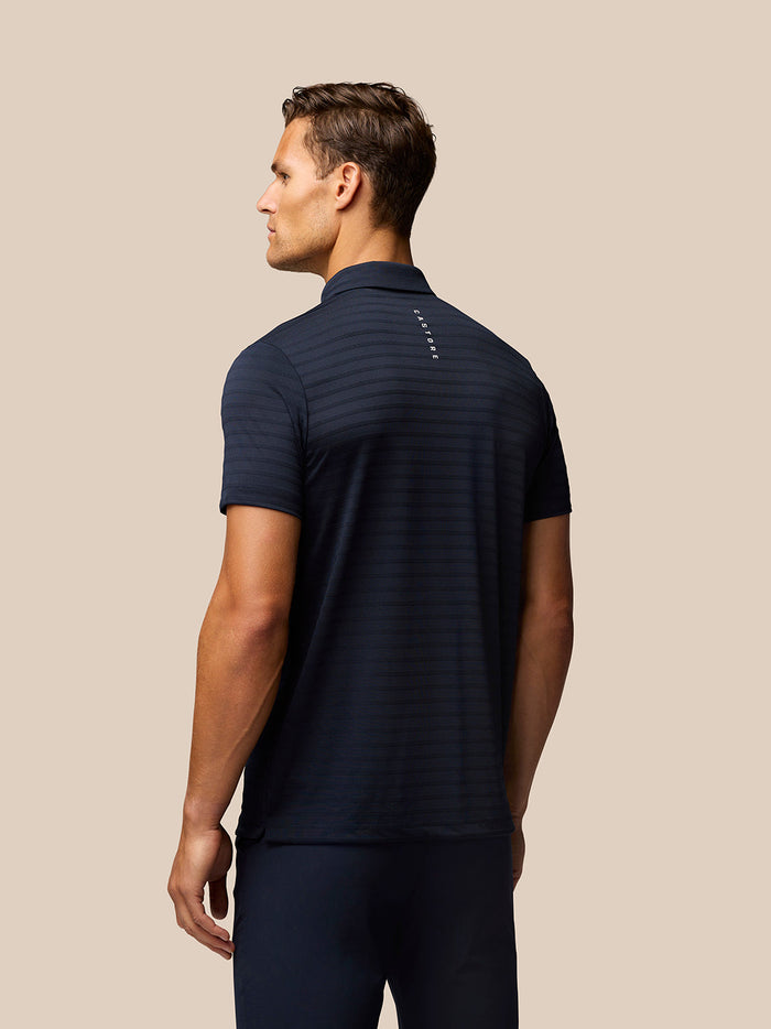 Back view of navy Pinnacle Pique Stripe Polo with subtle stripes and vertical Castore branding on the upper back.
