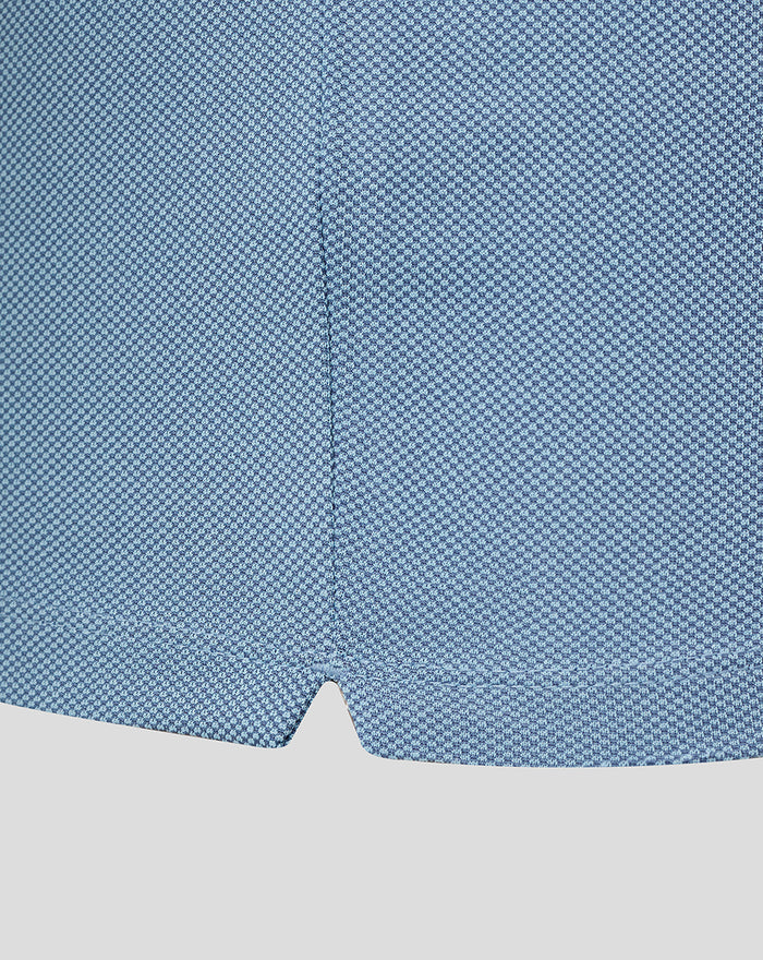 Close up of sky blue engineered knit golf polo fabric showing a fine textured weave and hem seam.