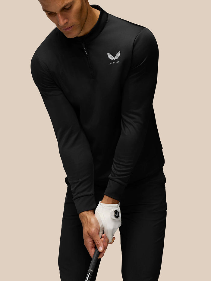 Close-up of a man in a black Castore Golf Club Classic 1/4 Zip Top showing the chest logo and stand collar.