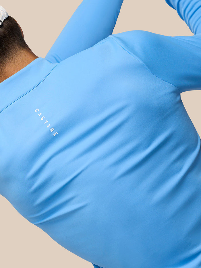 Back view of a person in a light blue Club Classic quarter-zip top with Castore branding along the upper back.