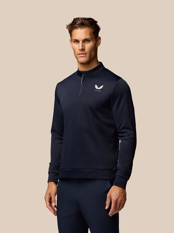 Man wearing midnight navy Golf Club Classic quarter-zip top with stand collar and Castore branding