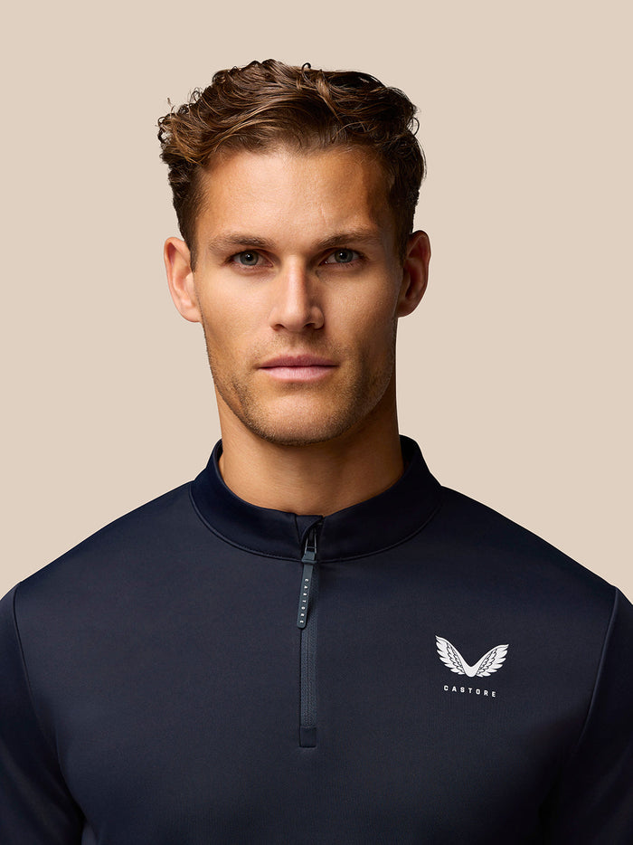 Front view of midnight navy Golf Club Classic 1/4 Zip Top on model showing front zip and Castore logo.