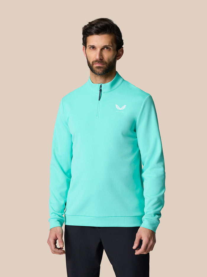 Male model wearing light aqua Golf Club Classic Quarter Zip Top with stand collar and Castore logo on the chest