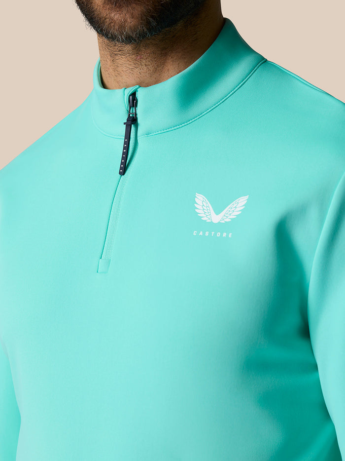 Close-up of light aqua Golf Club Classic Quarter Zip Top showing front zipper and Castore logo at left chest