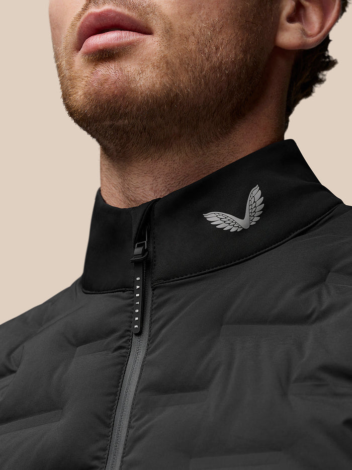 Close-up of the black Pinnacle Gilet neck area showing Castore wing logo on the collar and branded zipper pull