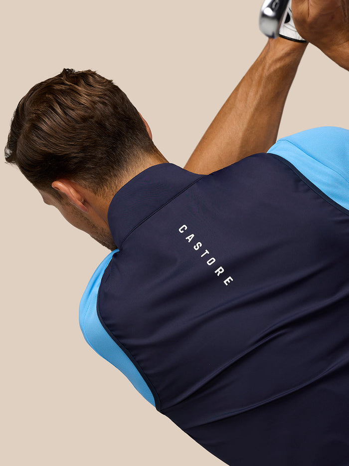 Back view of navy padded gilet with Castore lettering across the back and blue sleeves visible
