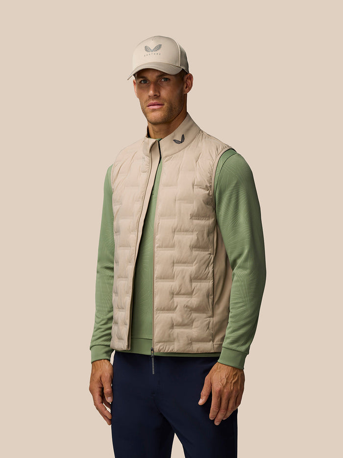 Male model wearing Mushroom Golf Pinnacle lightweight hybrid gilet with quilted front panels over a green top