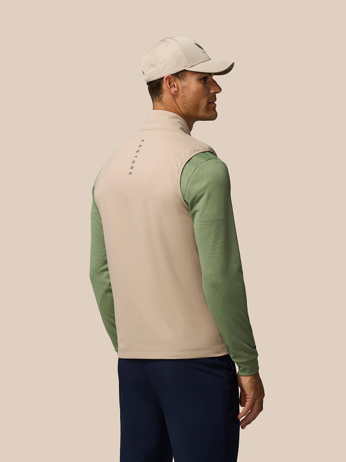 Back view of a man wearing mushroom Golf Pinnacle Gilet with Castore branding down the spine.