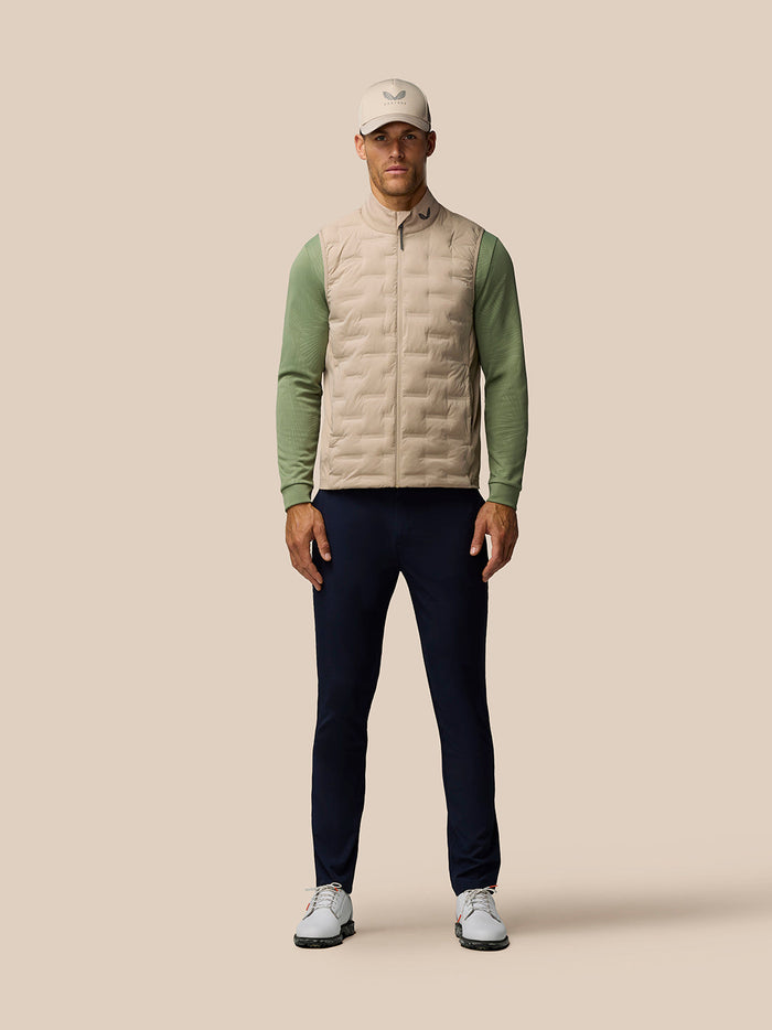 Front view of a man in mushroom Golf Pinnacle Gilet with quilted front panel and green sleeves.