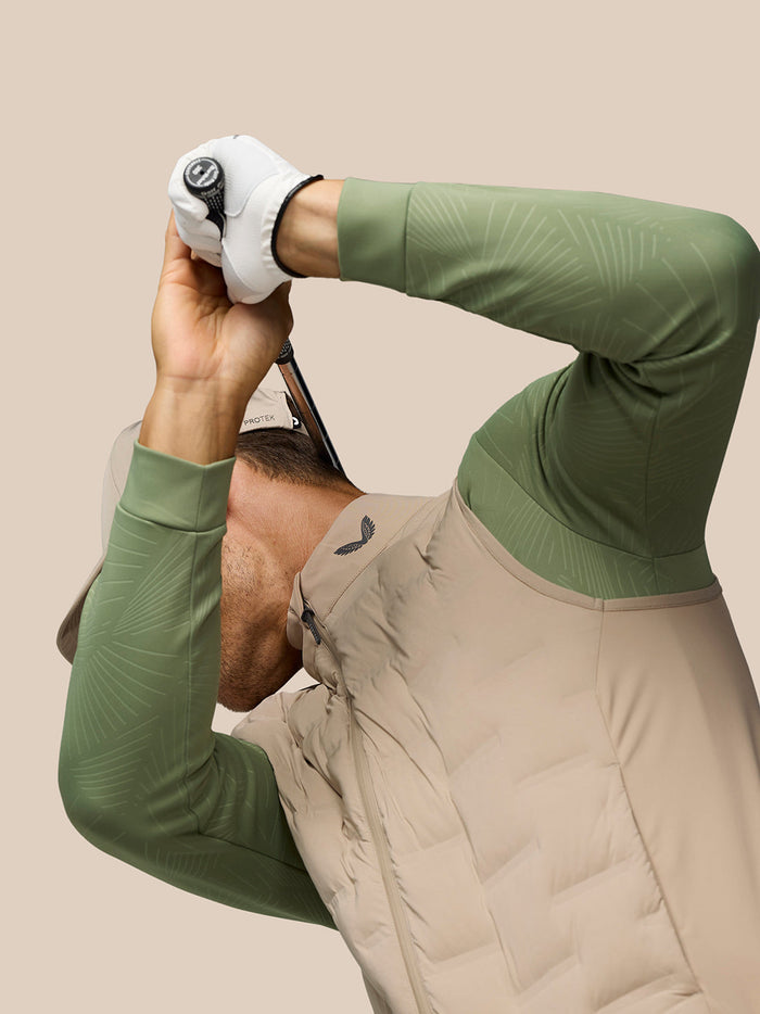 Golfer in Mushroom Pinnacle Gilet raises a club overhead during a swing